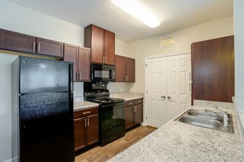 A kitchen with a black refrigerator, microwave, and stove.